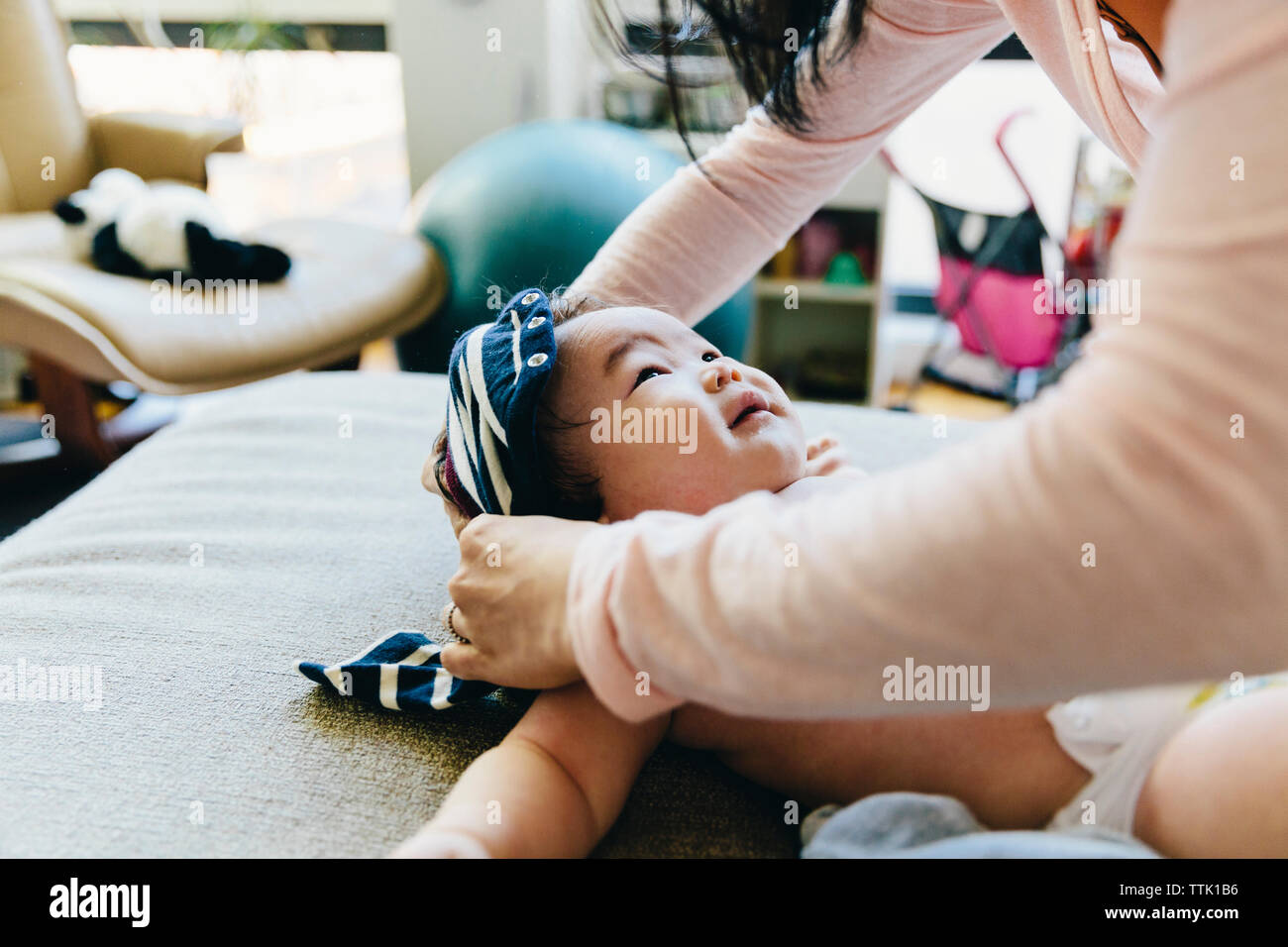 Sezione mediana della madre vestire il figlio sul letto di casa Foto Stock