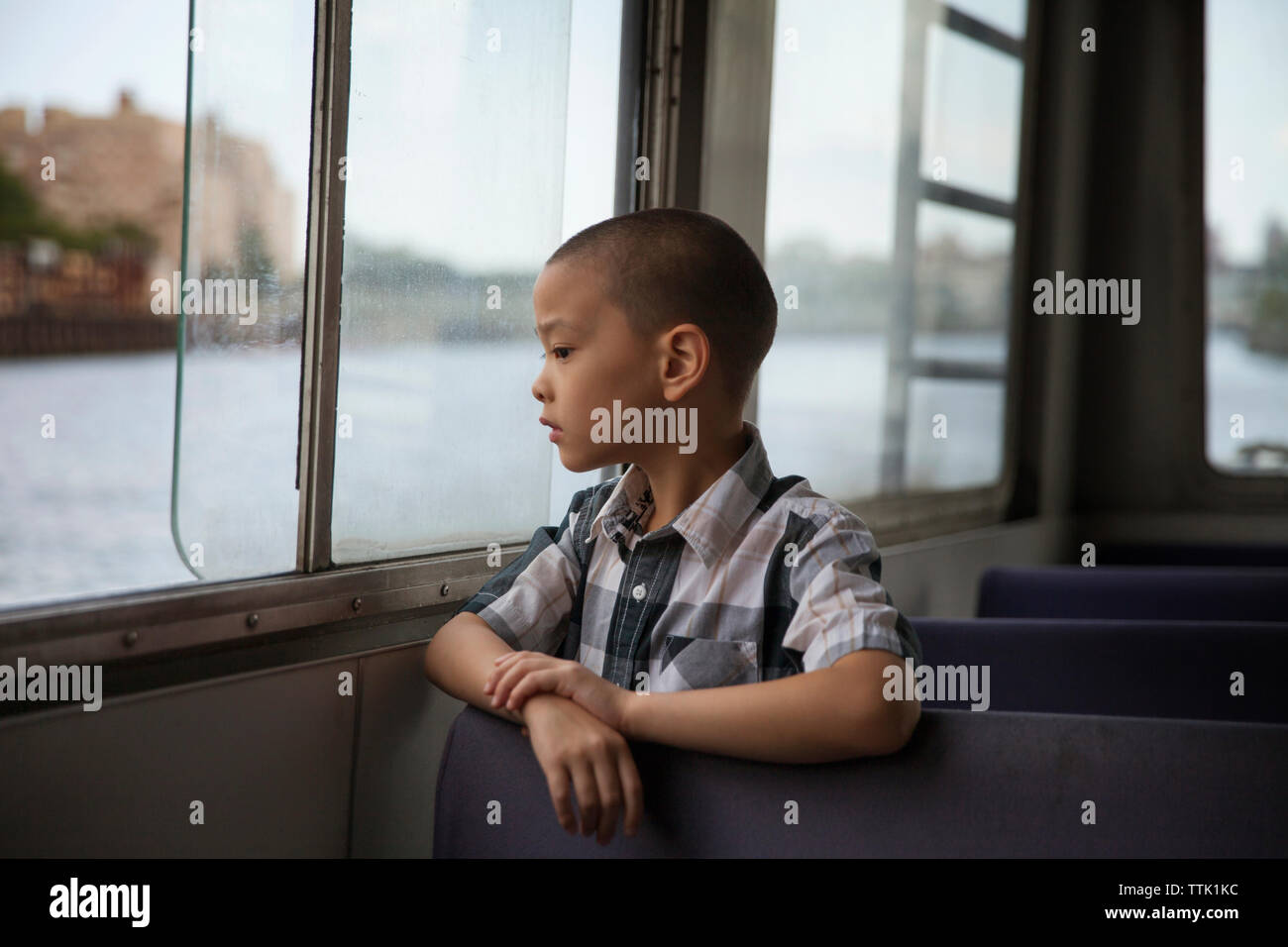 Riflessivo Ragazzo che guarda attraverso la finestra mentre si è in viaggio in traghetto Foto Stock