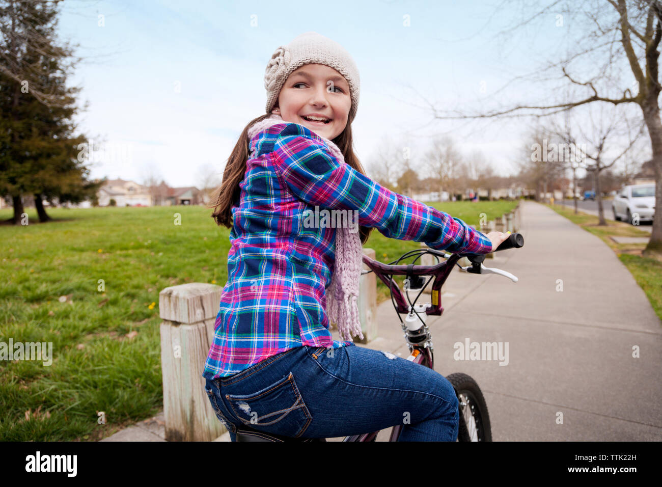 Felice ragazza ciclismo su strada dal campo erboso contro sky Foto Stock