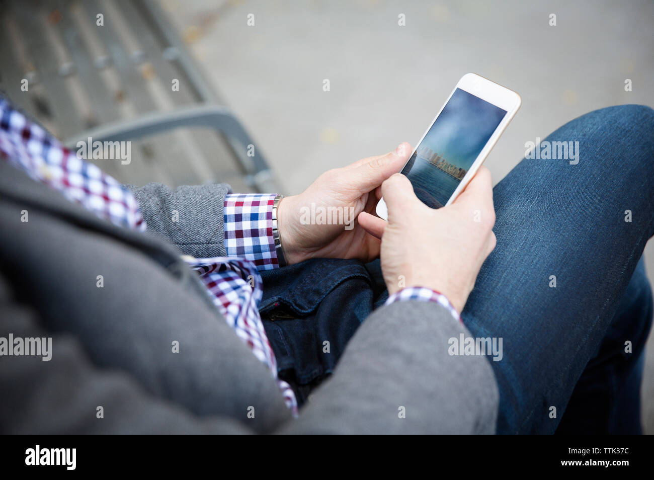 Sezione mediana dell'uomo utilizzando il telefono cellulare mentre è seduto su un banco di lavoro in posizione di parcheggio Foto Stock