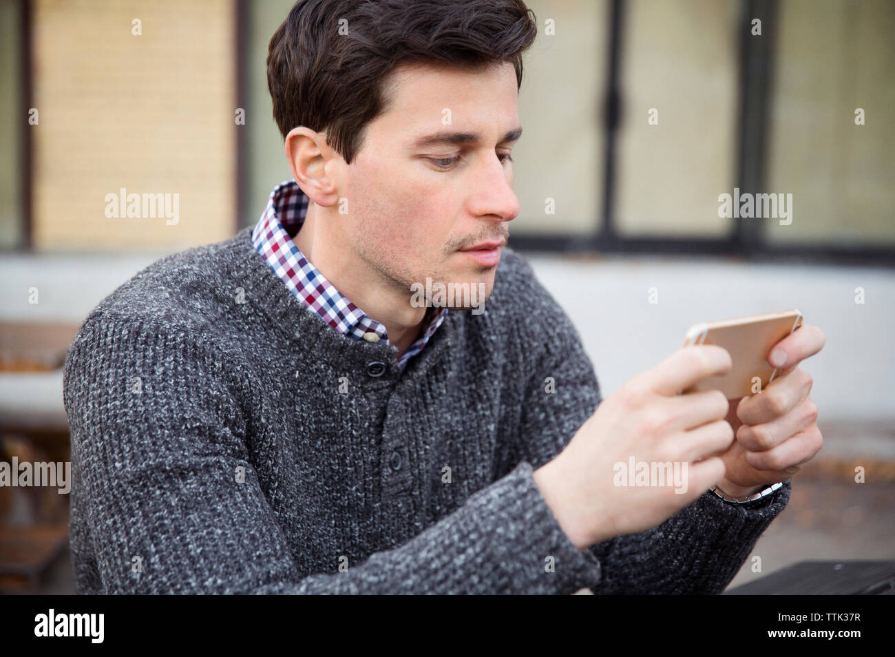 Uomo che utilizza il cellulare mentre seduti all'aperto Foto Stock