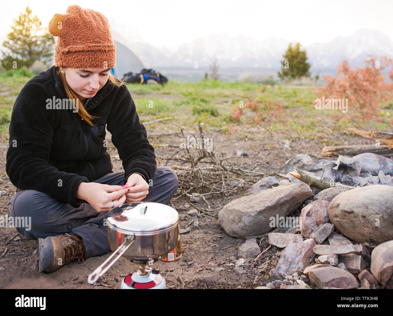 Donna rilassante dal fornello da campeggio Foto Stock