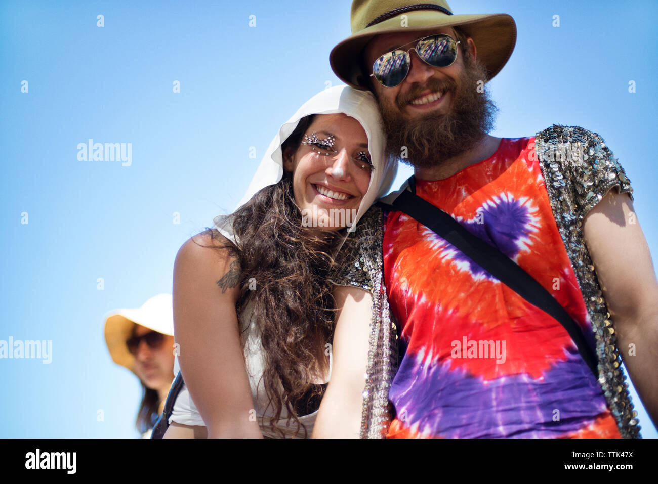 Basso angolo vista di allegro l uomo e la donna in piedi contro il cielo chiaro al tradizionale evento Foto Stock
