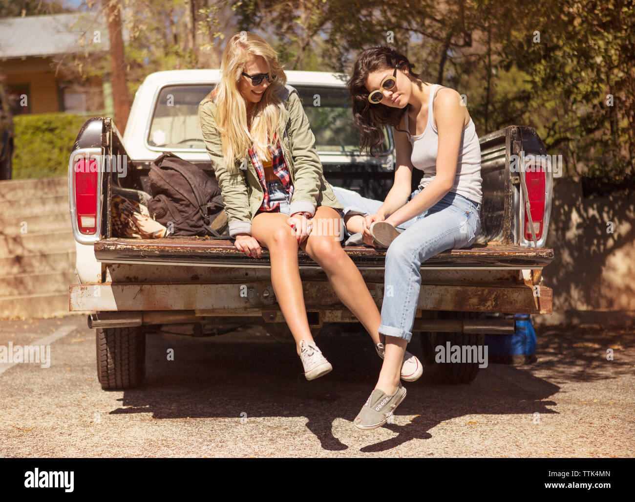 Happy amici di sesso femminile seduta sul tronco di veicolo durante la giornata di sole Foto Stock