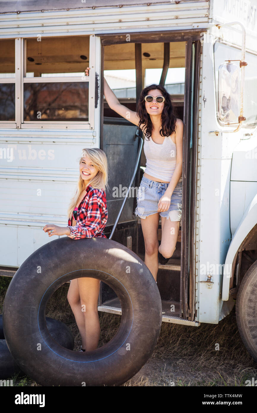 Ritratto di donna felice con un amico in piedi nel vecchio autobus Foto Stock