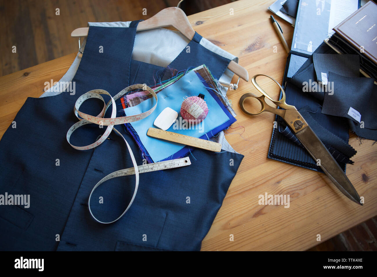 Angolo di alta vista del tessuto blu e le attrezzature sulla tavola in officina Foto Stock