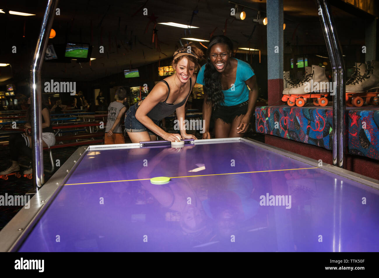 Gli amici sorseggiando air hockey club Foto Stock