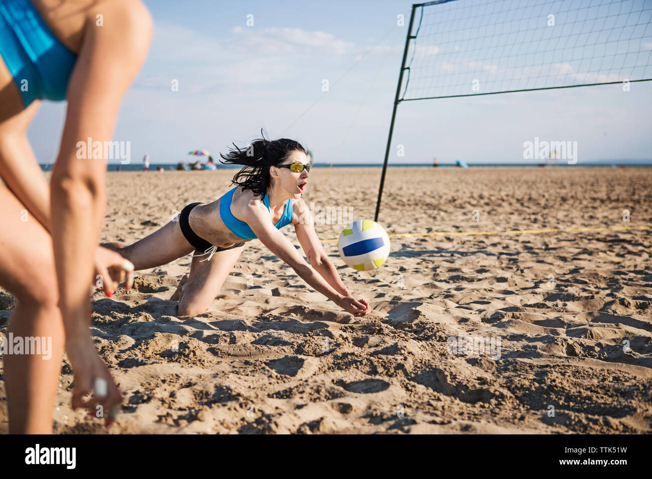 Amici di sesso femminile giocando a pallavolo in spiaggia sulla giornata di sole Foto Stock