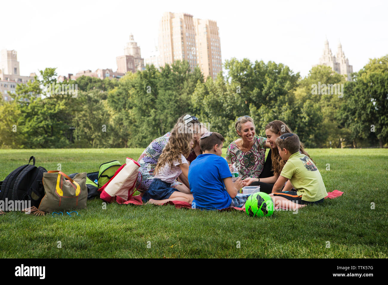 La famiglia e gli amici godendo picnic al parco in città Foto Stock