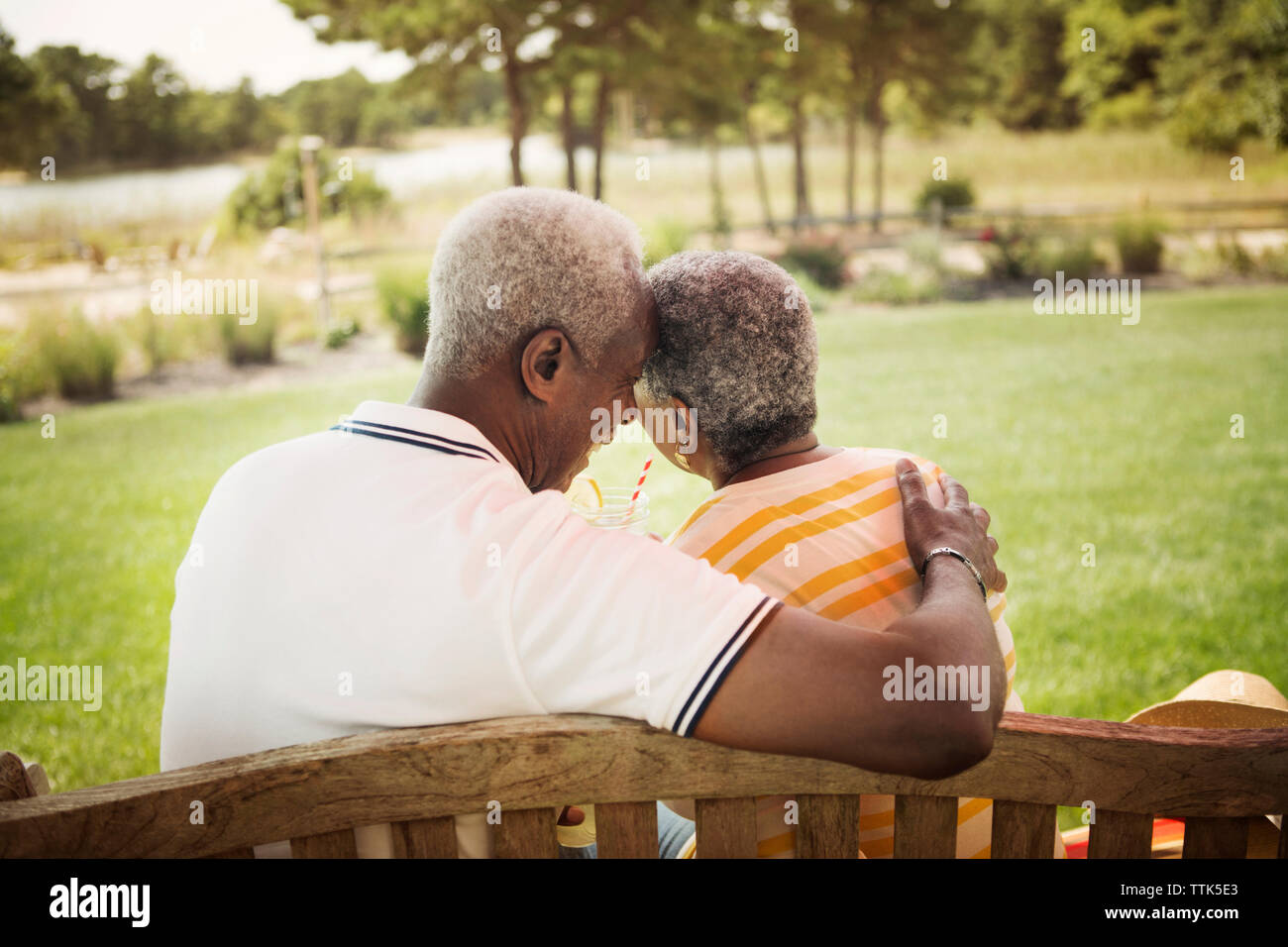 Vista posteriore della romantica coppia senior seduto su una panchina nel parco Foto Stock
