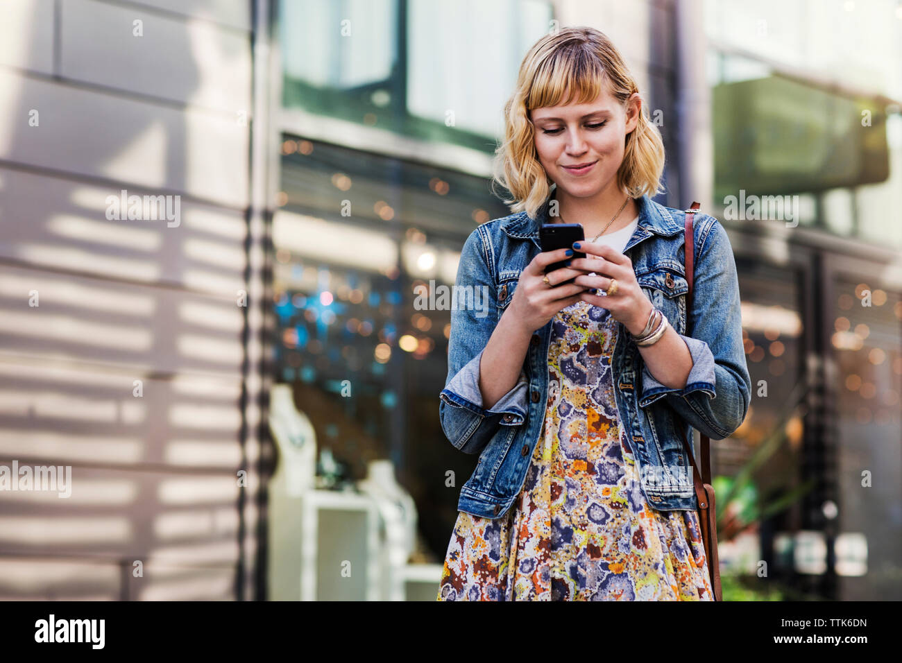 Donna che utilizza smart phone mentre in piedi Foto Stock