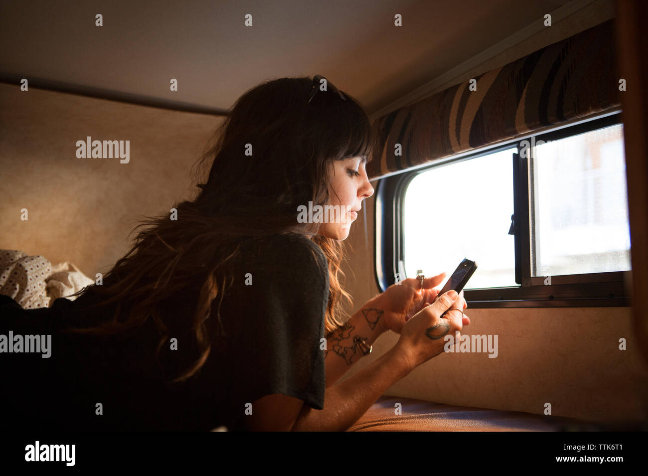 Donna che utilizza smart phone mentre vi rilassate sul letto in camper Foto Stock