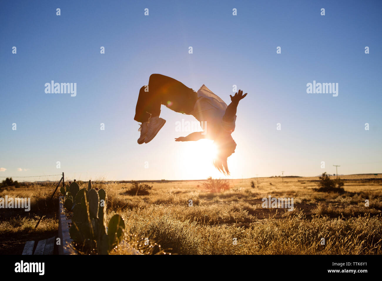 L'uomo facendo capriola sul campo contro il cielo chiaro Foto Stock