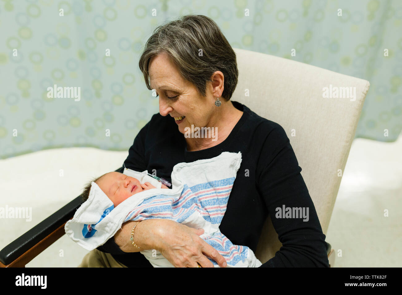 La nonna guarda sorridendo a un nipotino neonato nella stanza di ospedale Foto Stock