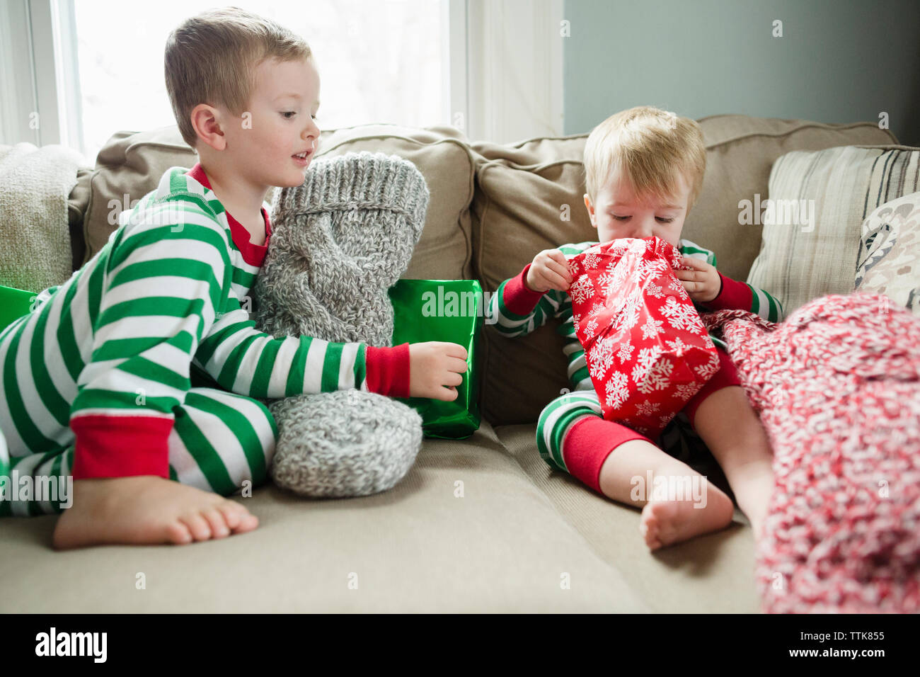 Il Toddler boy guarda al presente egli è apertura a casa il giorno di Natale Foto Stock