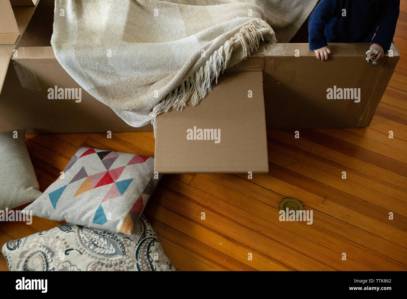 Bambino gioca in ambienti interni in aeroplano di cartone coperto con coperta Foto Stock