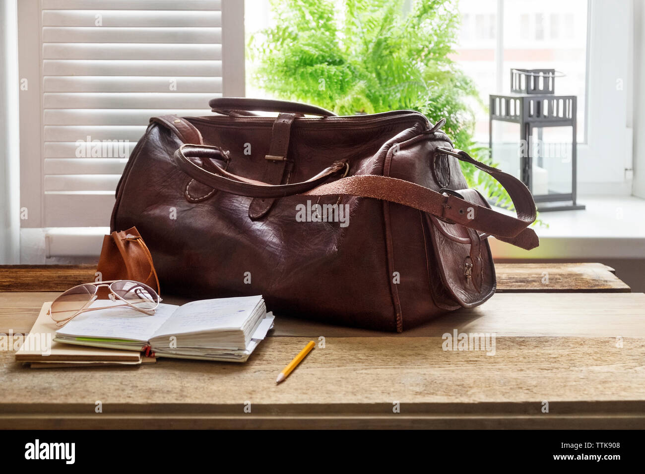 Borsa in pelle e i libri sul tavolo in ufficio a casa dalla finestra Foto Stock