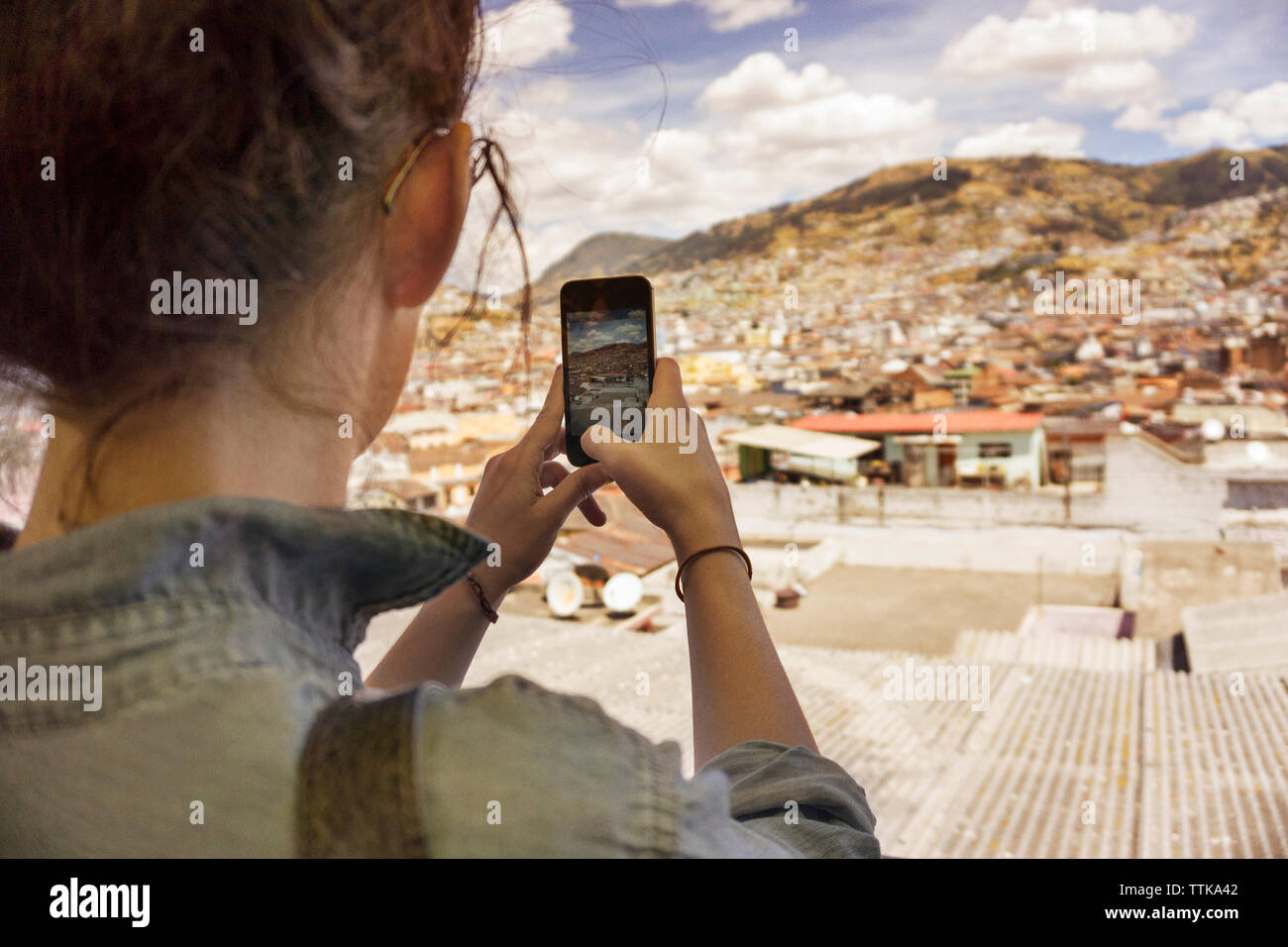 Vista posteriore della donna fotografare quartiere residenziale con smart phone contro sky Foto Stock