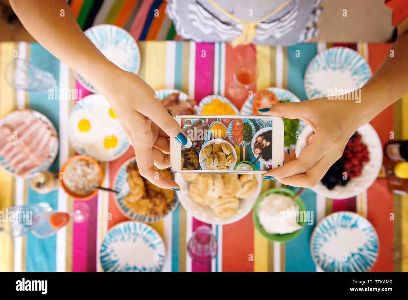 Immagine ritagliata della donna con le mani in mano a fotografare il cibo in tavola Foto Stock