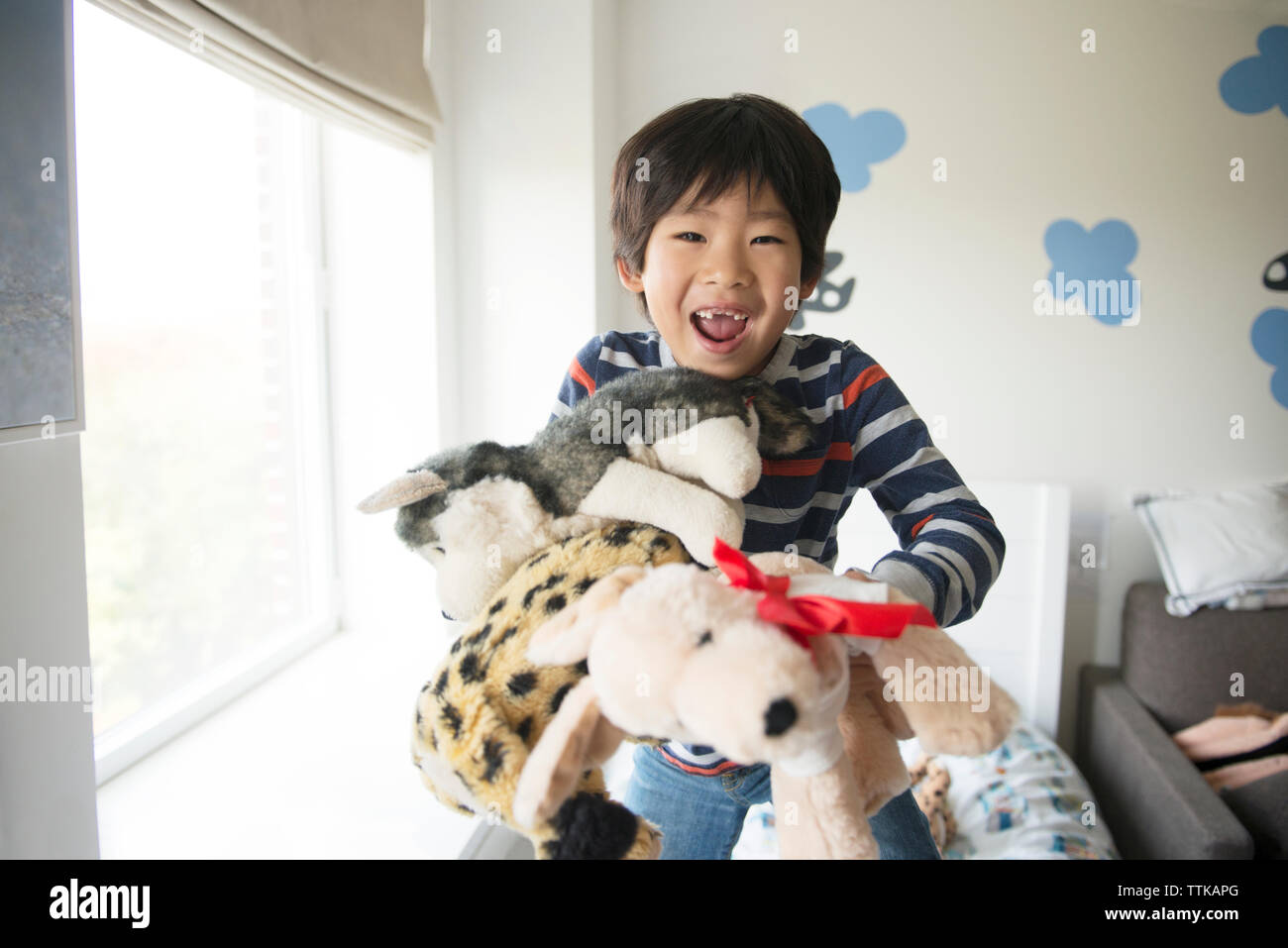 Felice ragazzo giocando con i giocattoli imbottiti dalla finestra a casa Foto Stock