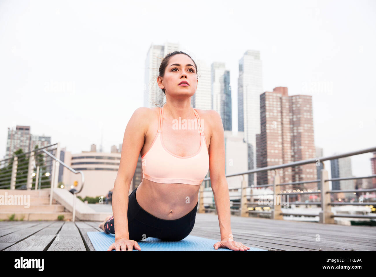 Donna facendo cobra pongono sul ponte in città Foto Stock