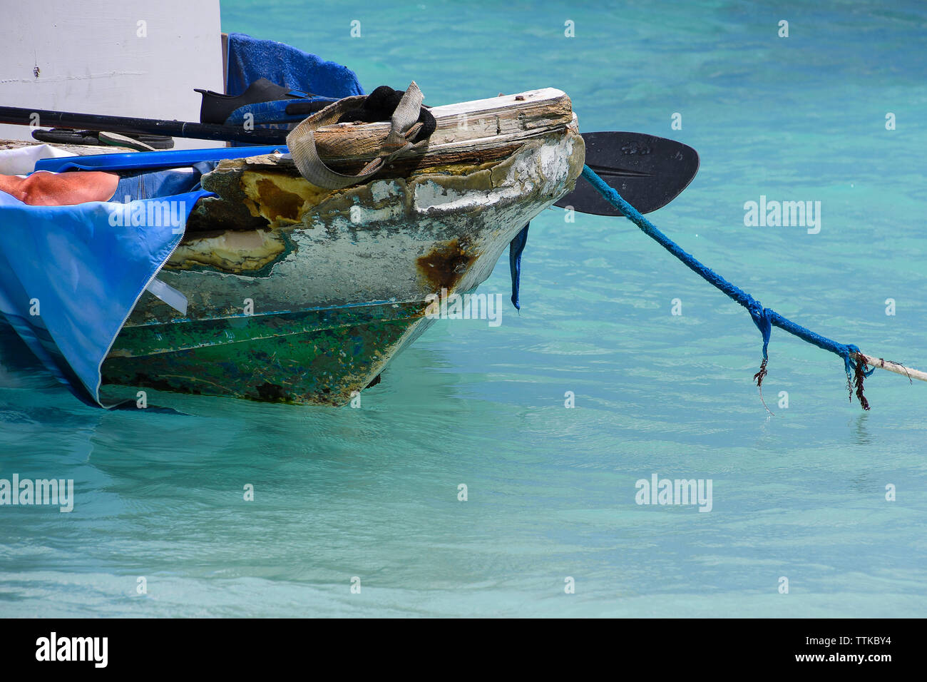 Vecchia barca da pesca riempito con junk ormeggiata dalla corda sfilacciata in oceano turchese acqua Foto Stock