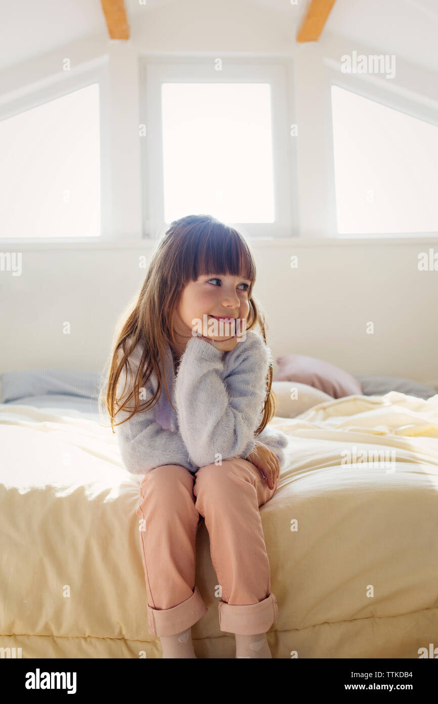 Premurosa ragazza seduta sul letto di casa Foto Stock