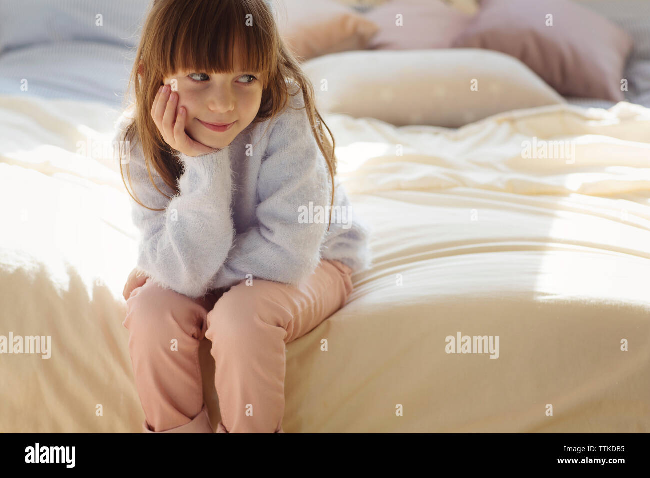 Premurosa ragazza seduta sul letto Foto Stock