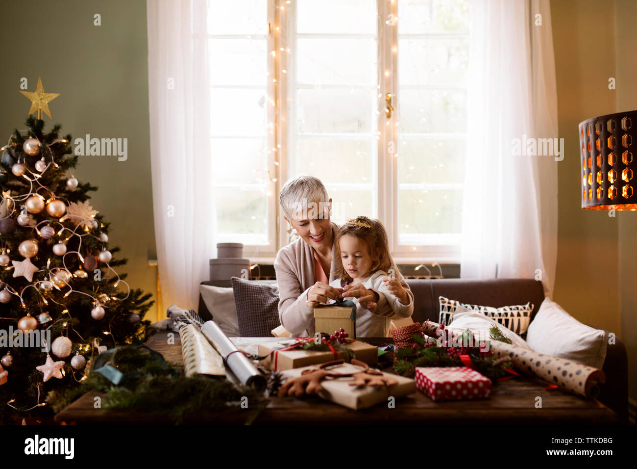 Nonna che aiuta la ragazza a fare il regalo durante il natale Foto Stock