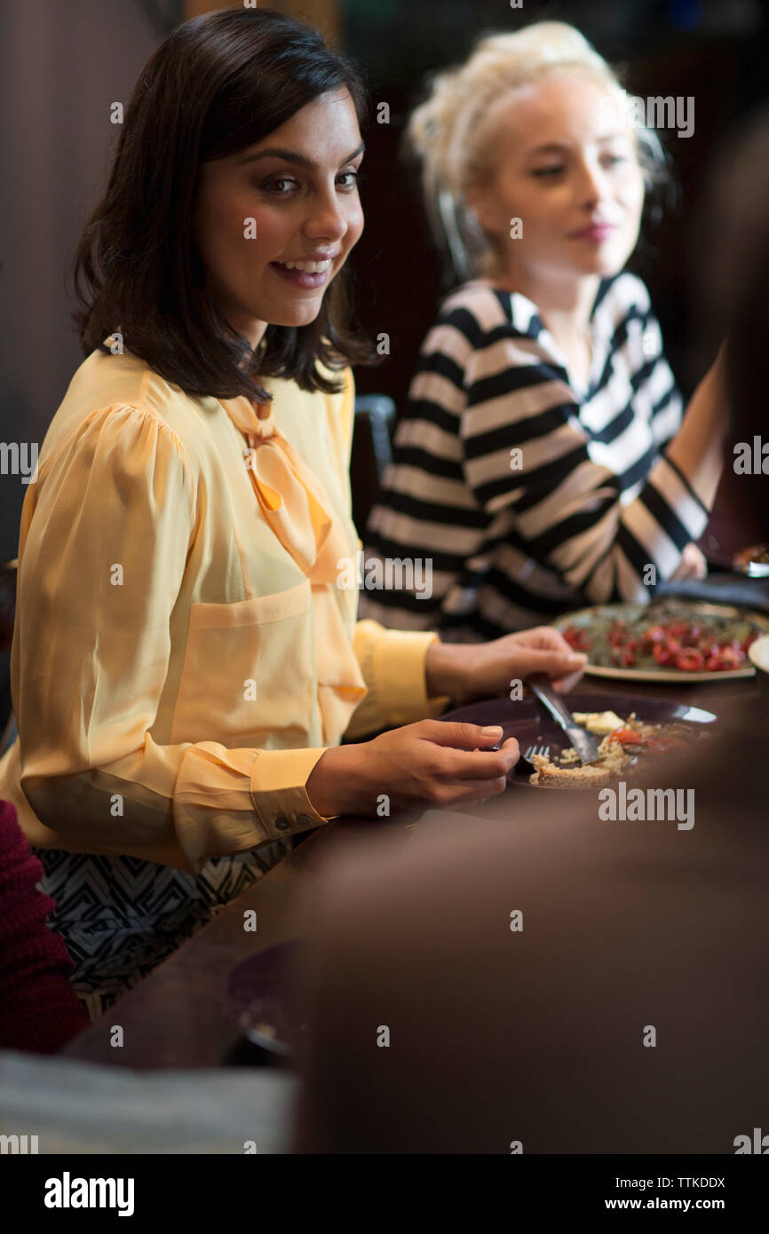 Donna sorridente che cena con gli amici a casa durante il natale Foto Stock