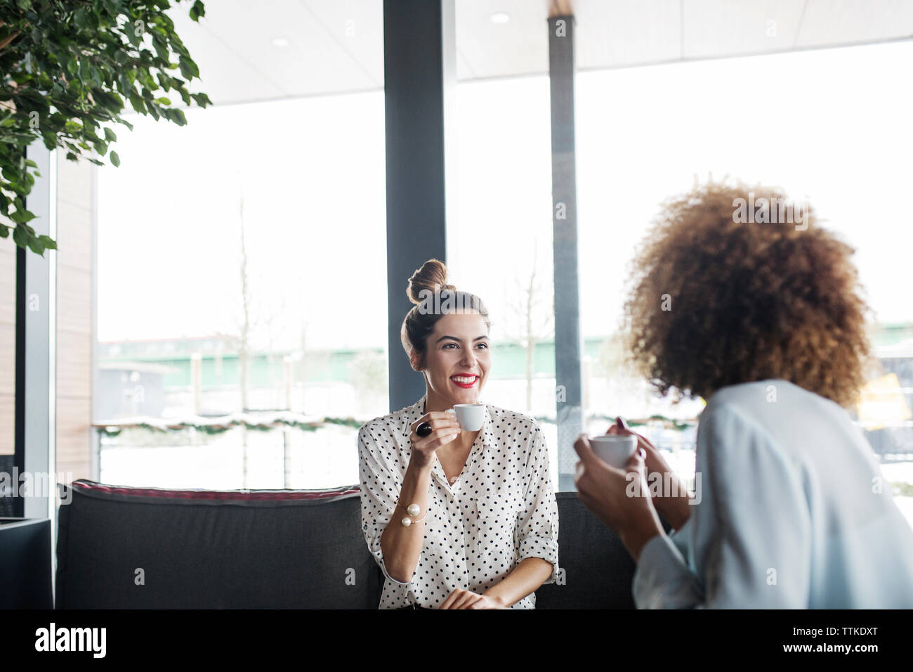 Felice imprenditrice guardando collega tenendo tazza di caffè presso il cafe Foto Stock