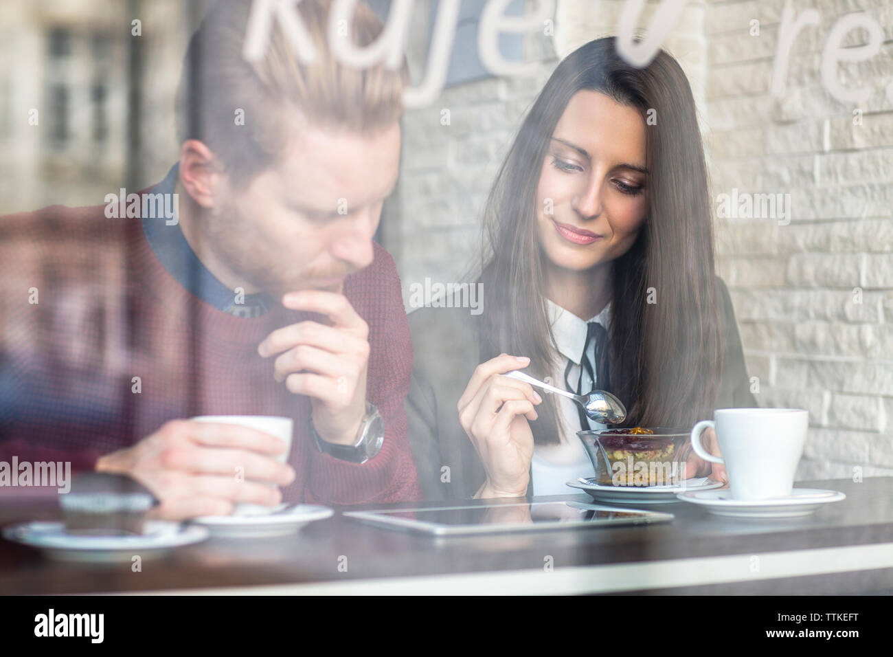 coppia di lavoro che usa un tablet al ristorante visto dalla finestra di vetro Foto Stock