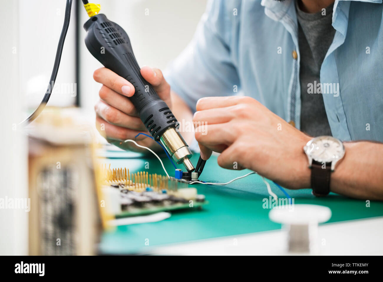 Sezione mediana del tecnico che sta lavorando al tavolo nell industria elettronica Foto Stock