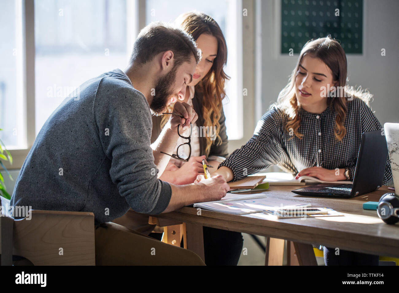 Gli studenti universitari che studiano seduti a tavola in aula Foto Stock