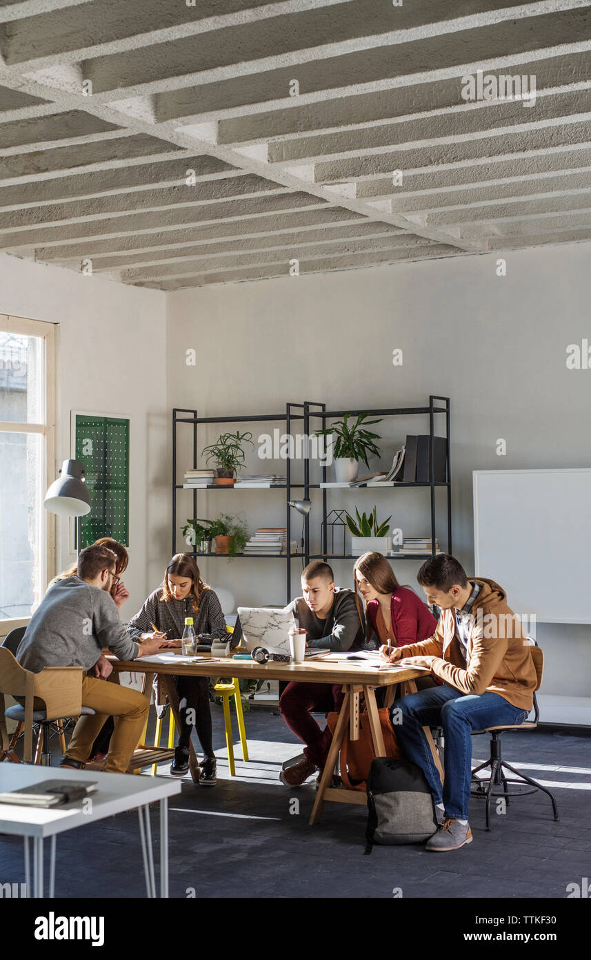 Gli studenti che studiano a tavola dalla finestra in aula Foto Stock