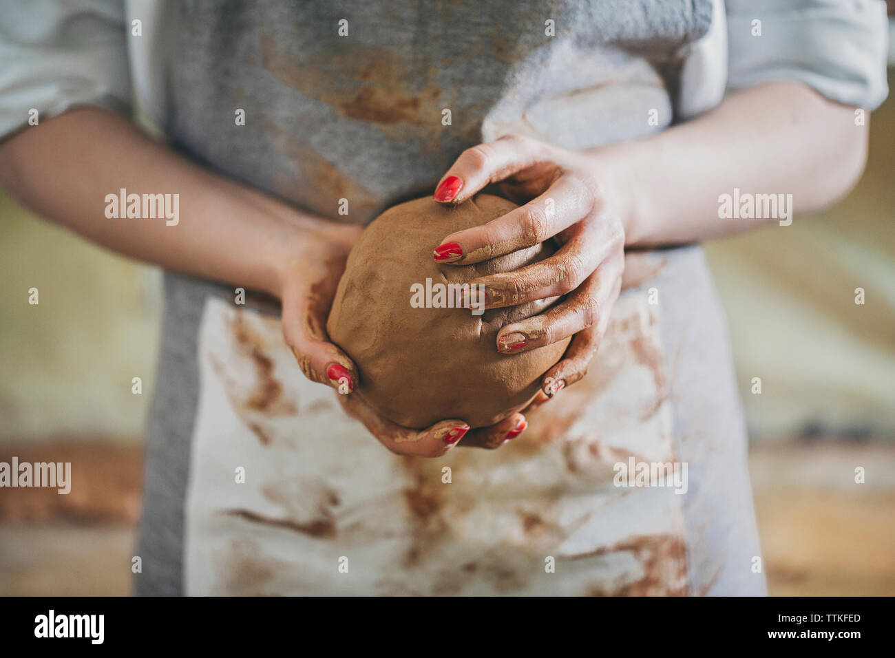 Sezione mediana del potter femmina di argilla di contenimento mentre in piedi in officina Foto Stock