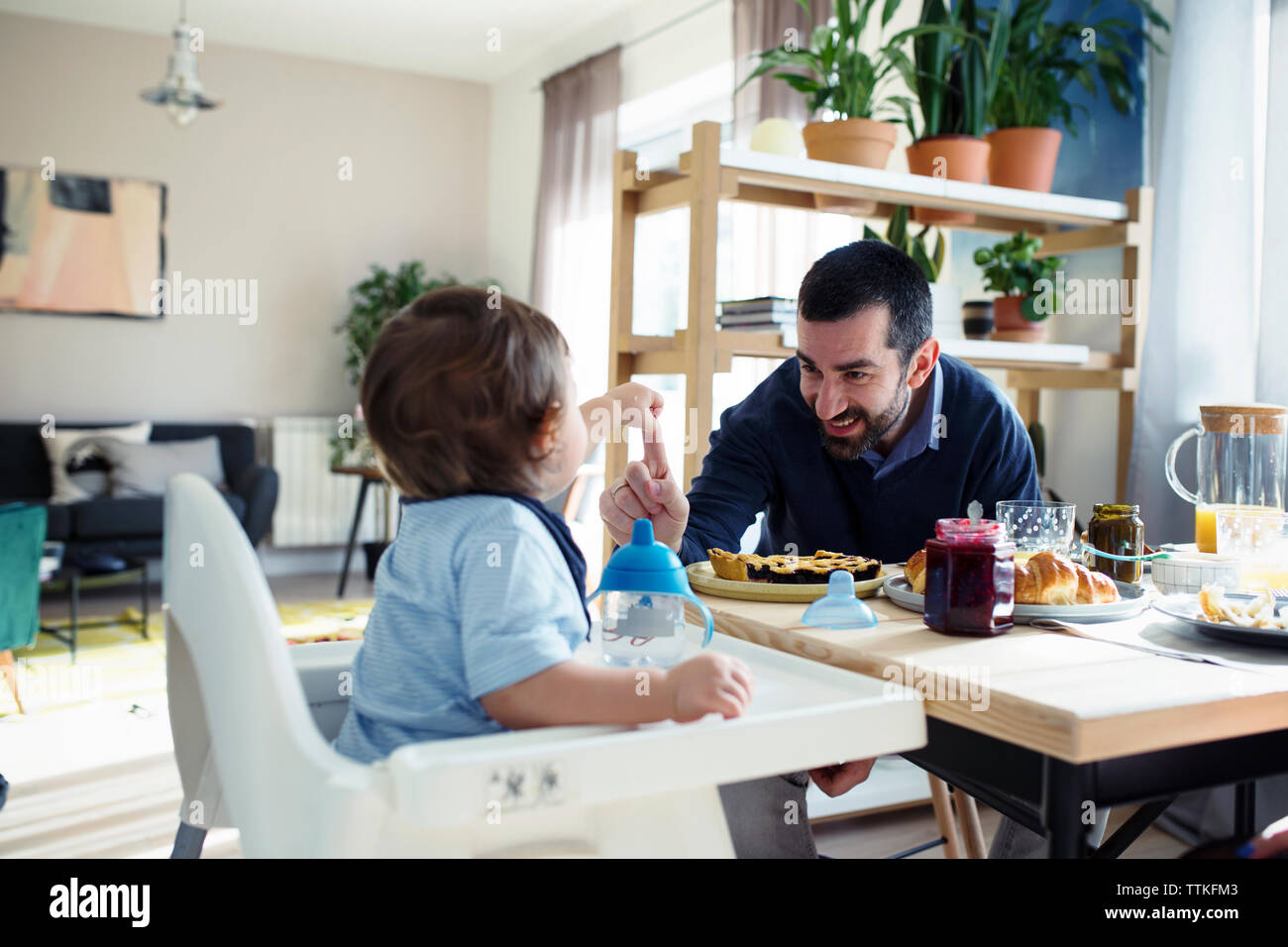 Padre Felice giocando con il figlio mentre si consuma la colazione a casa Foto Stock
