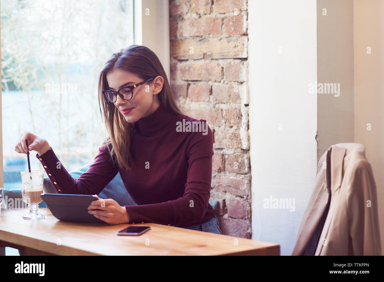 Donna che utilizza computer tablet seduti dalla finestra nel cafe Foto Stock
