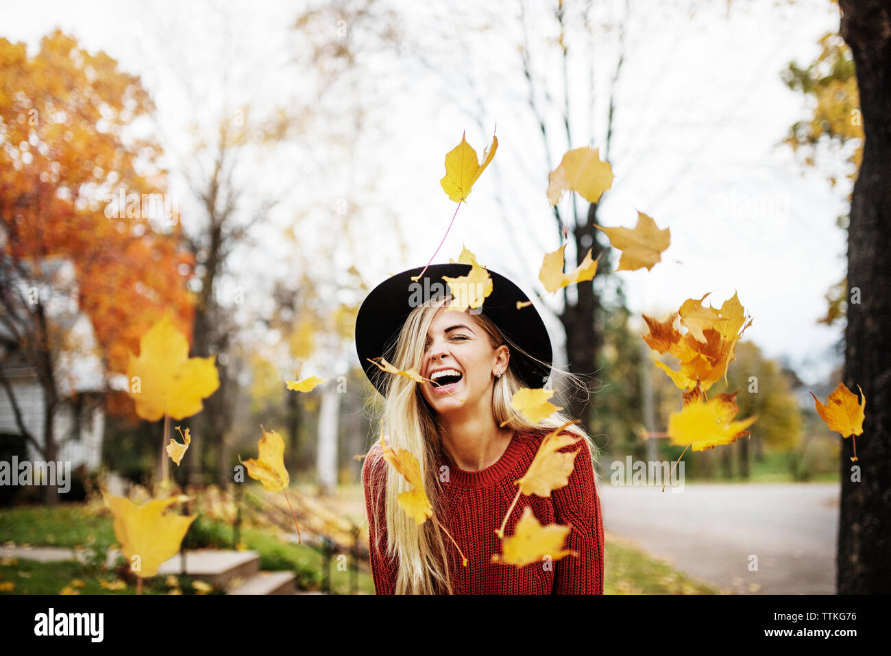 Felice donna in piedi in mezzo a battenti Foglie di autunno Foto Stock