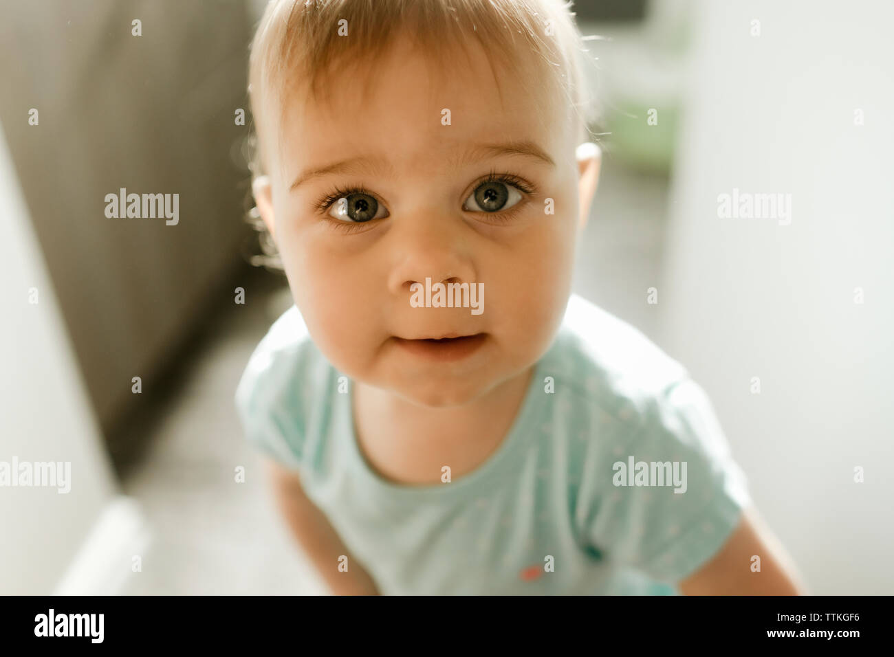 Baby girl in piedi nella porta leggermente sorridente fino Foto Stock