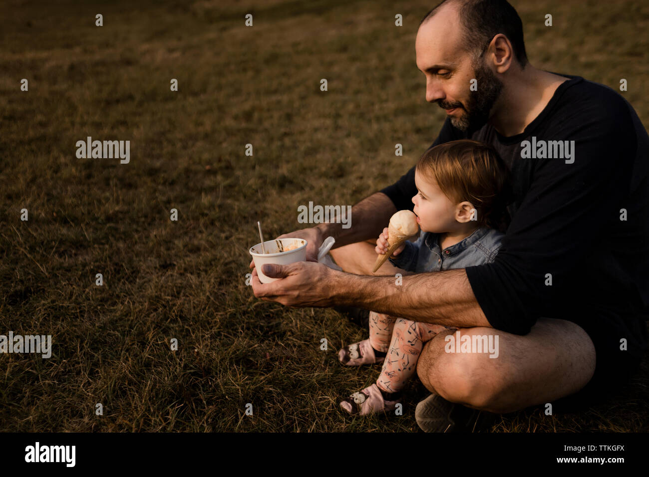 Padre e figlia a mangiare il gelato su una collina in estate Foto Stock