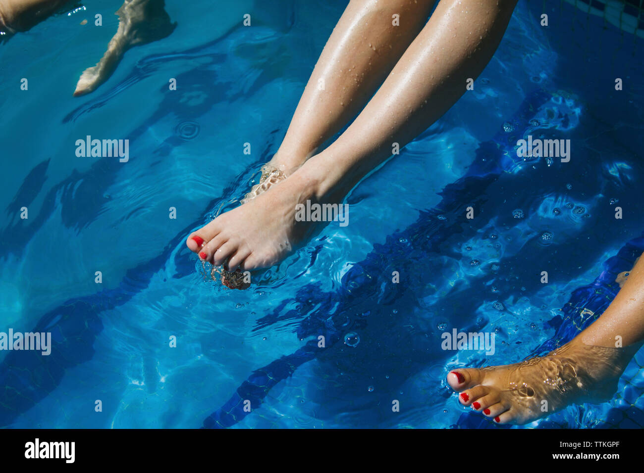 Donna gambe penzolanti in piscina Foto Stock