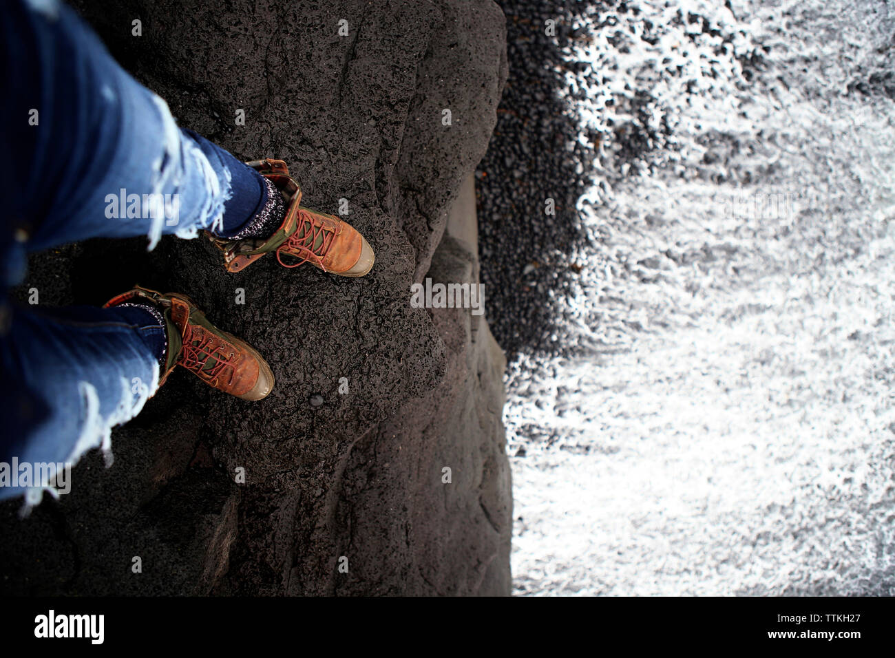 Sezione bassa della donna in piedi sulla scogliera dal mare Foto Stock