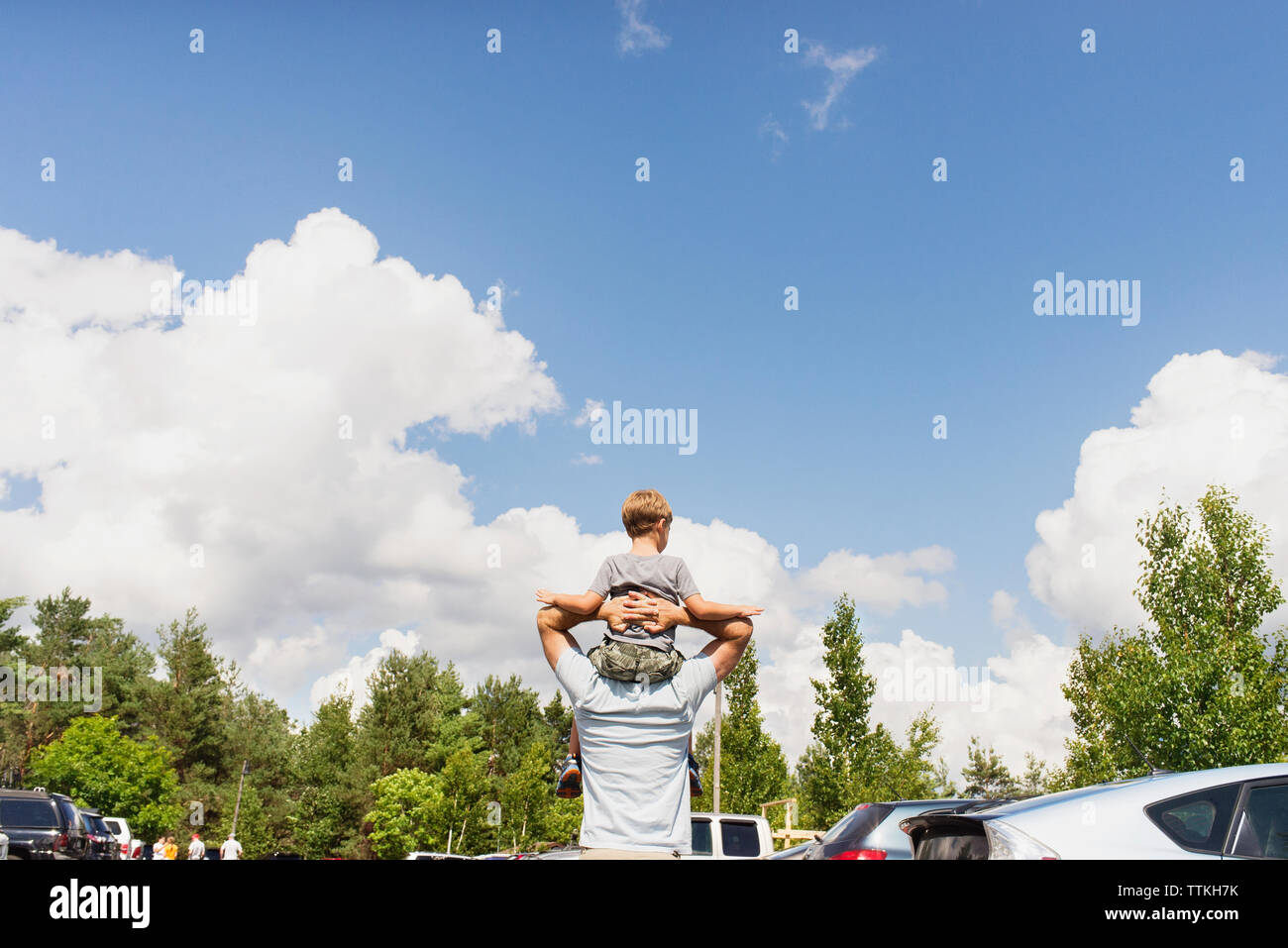 Vista posteriore dell'uomo figlio che porta sulle spalle contro il cielo nuvoloso Foto Stock