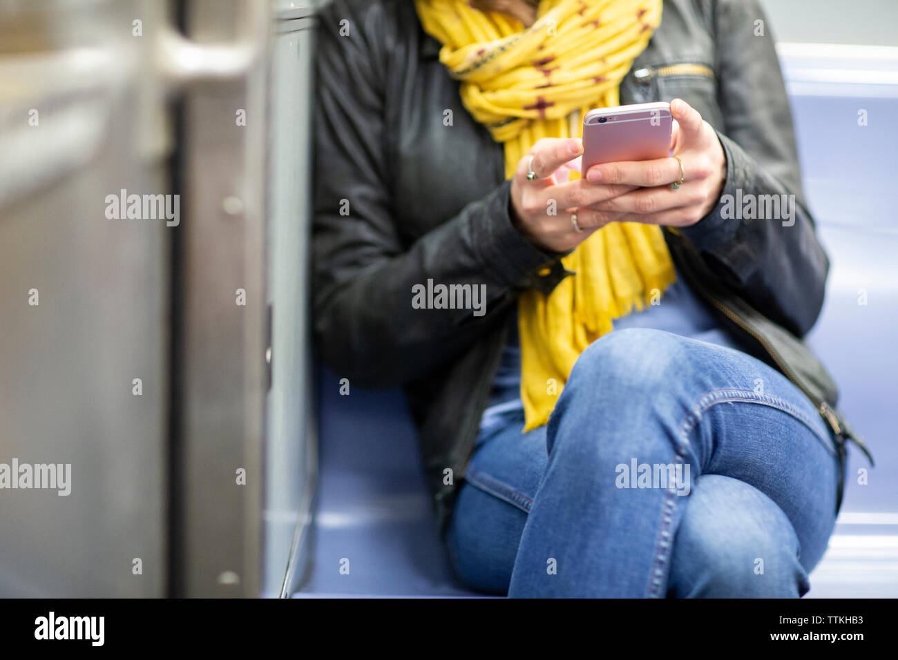 Sezione mediana della donna utilizzando smart phone durante il viaggio in treno Foto Stock