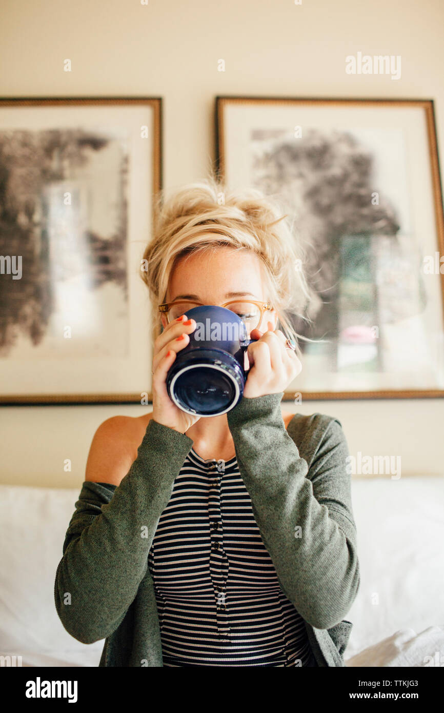 Donna con drink seduto sul letto Foto Stock