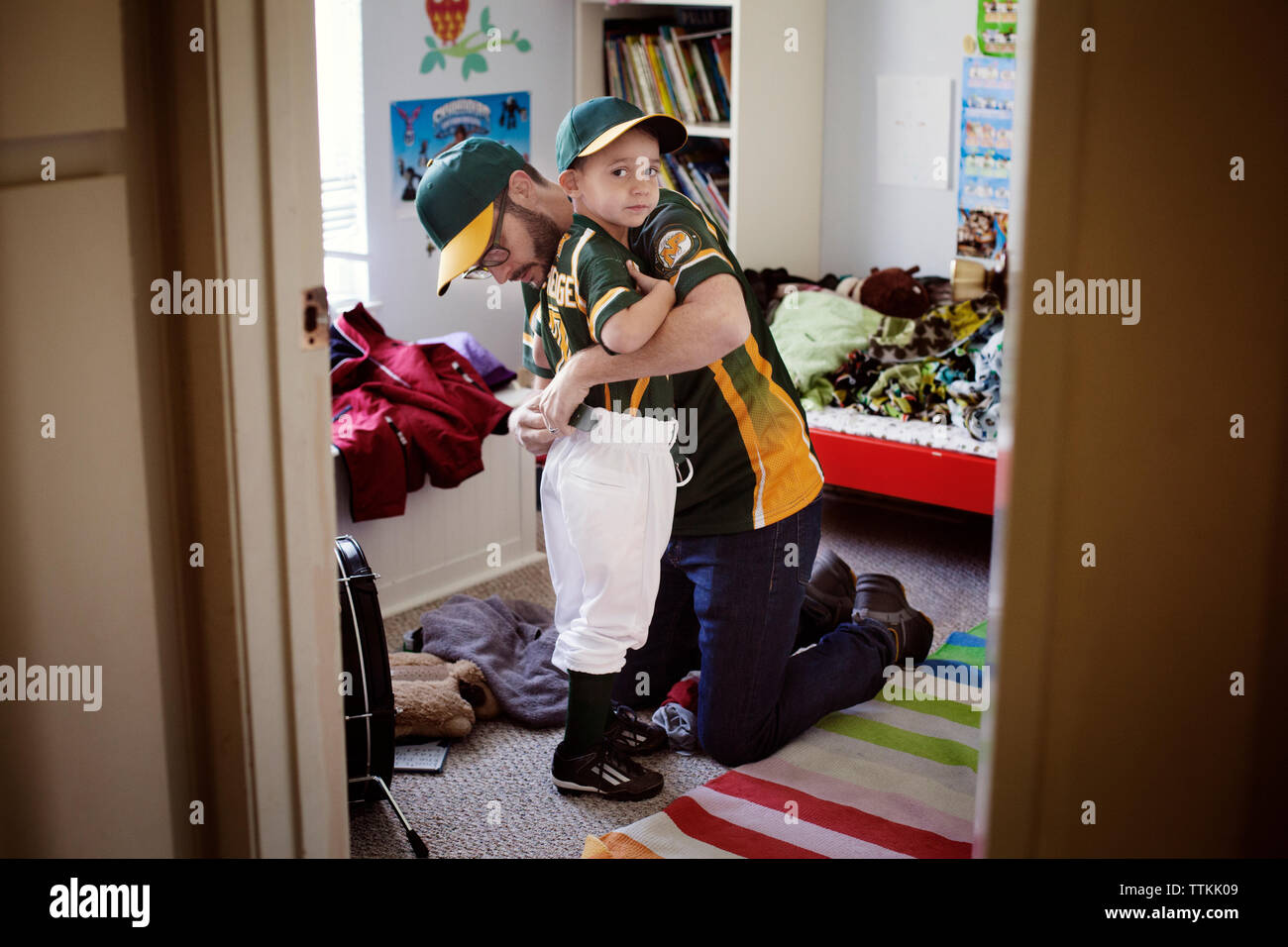Padre vestire il figlio in camera da letto Foto Stock