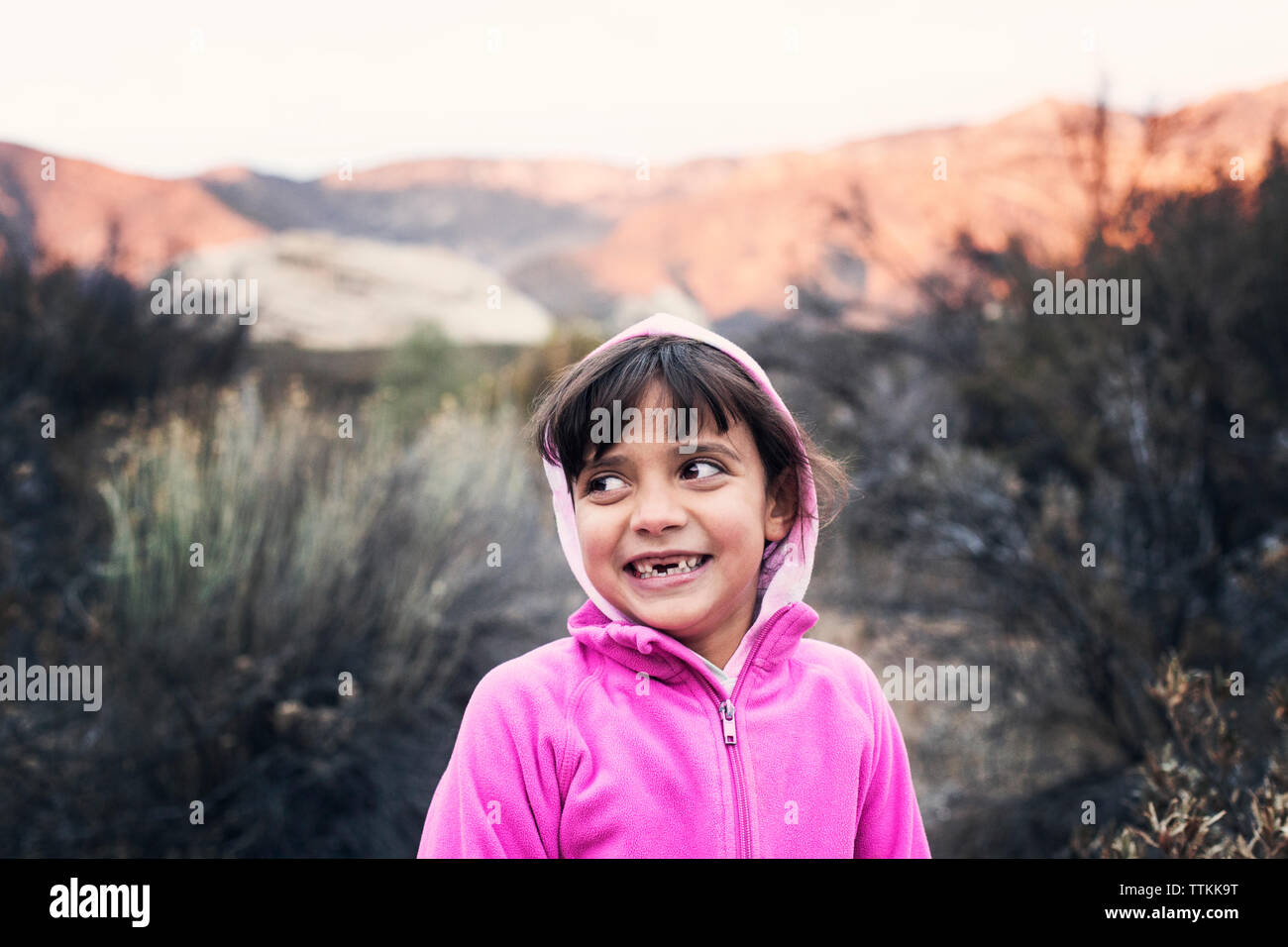 Felice ragazza indossando la cappa rosa mentre si sta in piedi sul campo Foto Stock