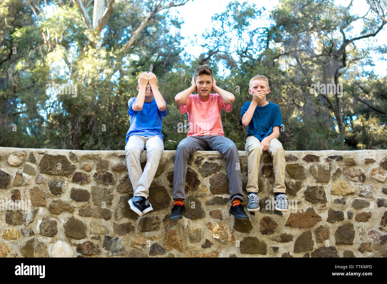 Tre ragazzi seduti su una parete vedere alcun male, non sento, non parlo Foto Stock
