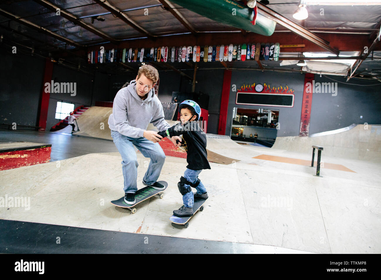 Tenendo entrambe le mani, skateboard istruttore guida studente Foto Stock